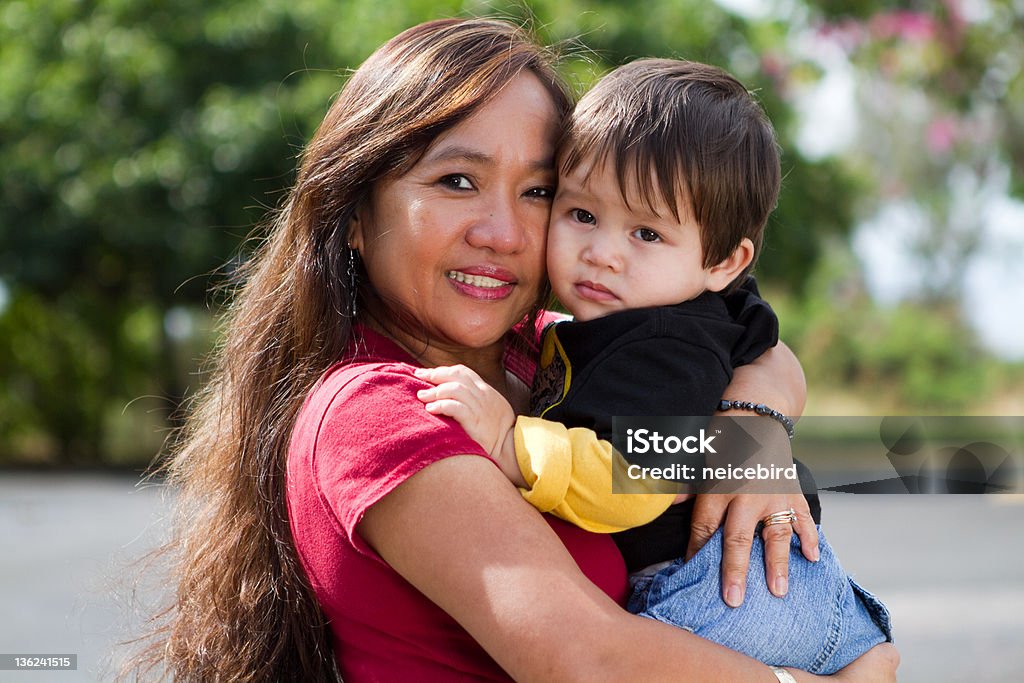 Grandma Hugging Child This young looking Filipino grandmother is hugging her grandson outside in the warm sunshine of Hawaii. Pacific Islanders Stock Photo
