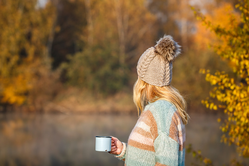 Camping and hiking outdoors in forest. Blond hair woman wearing knit hat and sweater