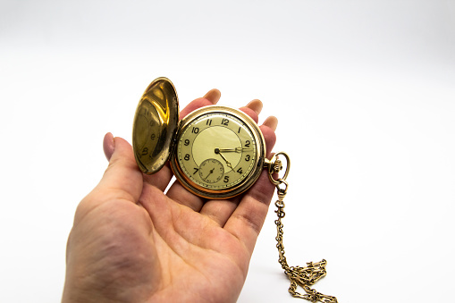 Vintage golden old pocket watch on the hand against white background. Hand hold a retro watch