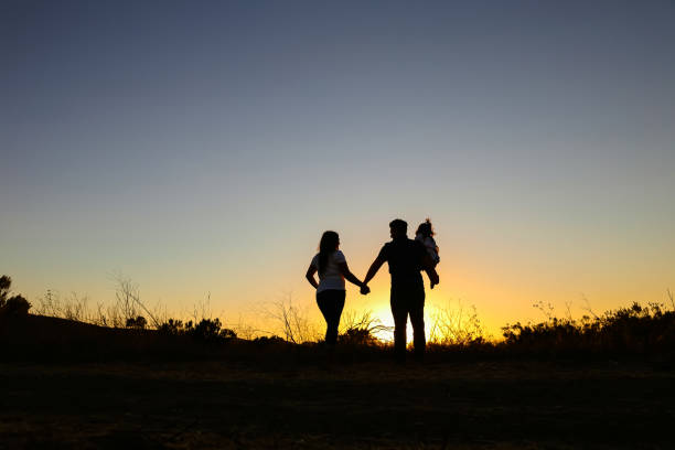 istock Family of three at sunset silhouette 1362427355