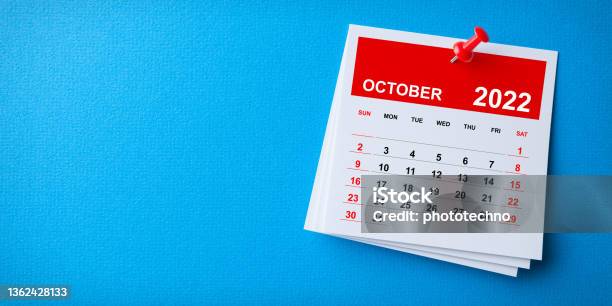 White Sticky Note With 2022 October Calendar And Red Push Pin On Blue Background Stock Photo - Download Image Now