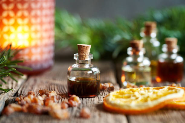 a bottle of myrrh essential oil with myrrh resin, orange and fir in the background - tree resin imagens e fotografias de stock