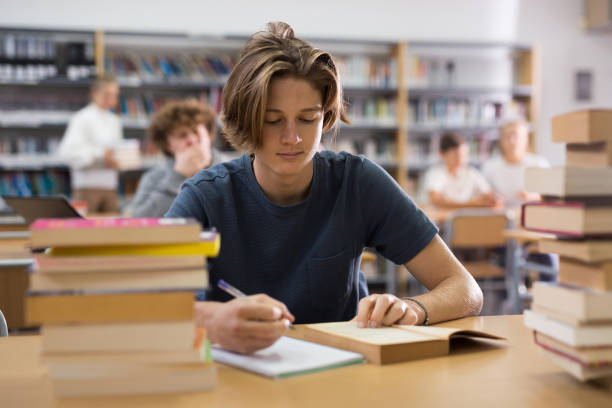 istock Teenager boy spending time in library 1362431406