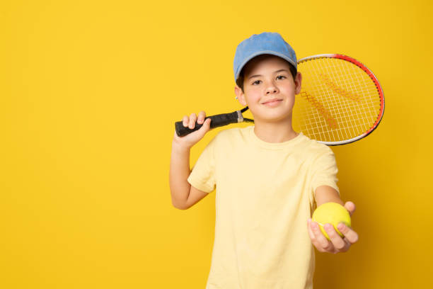 istock Smiling boy playing tennis holding racket isolated on yellow background 1362432540