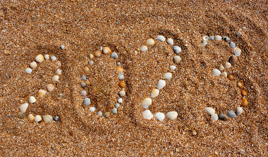 The numbers 2023 on the sea sand are lined with small shells.New Year's concept.