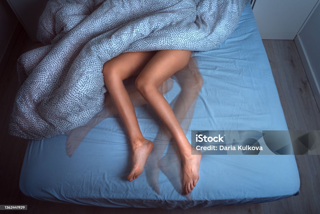 Woman sleeping in the bed and suffering from RLS or restless legs syndrome Woman sleeping in the bed and suffering from RLS or restless legs syndrome. High quality photo Leg Stock Photo