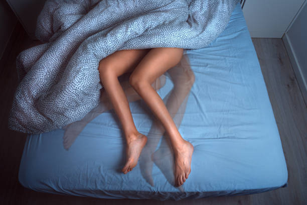 woman sleeping in the bed and suffering from rls or restless legs syndrome - leg imagens e fotografias de stock