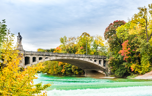 Turquoise Isar river and autumn landscape of maximilian bridge in Munich - Germany