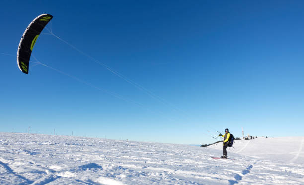 sportivo invernale sulla neve. snow kiter con un sonic di flysurfer sugli sci davanti al cielo blu. in una soleggiata giornata invernale nella foresta nera. - black forest forest sky blue foto e immagini stock