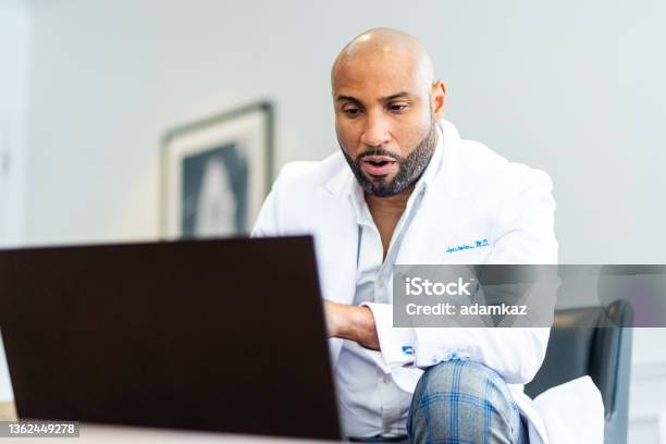 Black Male Radiologist Doctor Reading X Ray Images On Laptop From Home Stock Photo - Download Image Now