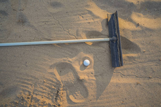 concept de golf. balle de golf et sable râteau sur bunker dans un magnifique parcours de golf au coucher du soleil - sand trap golf sand trap photos et images de collection