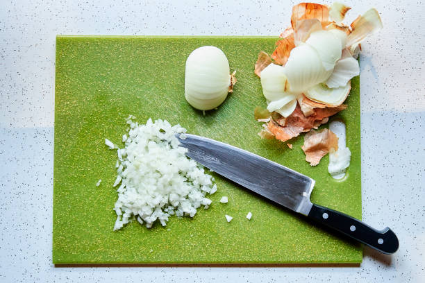vista dall'alto della cipolla tagliata a dadini e del coltello dello chef sul tagliere di plastica verde - leek green raw food foto e immagini stock