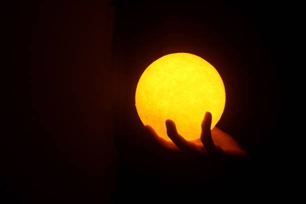 istock Warm light of ball lamp in hand on dark background. 1362471382