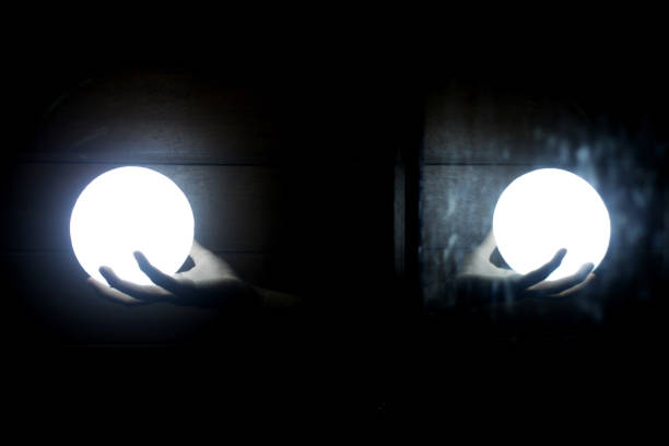 Person white holding ball lamps in hands with light mirror shadow in the dark on black and white abstract art background.