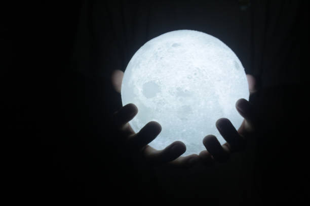 istock Warm white light of ball lamp in hand on dark background. 1362471441