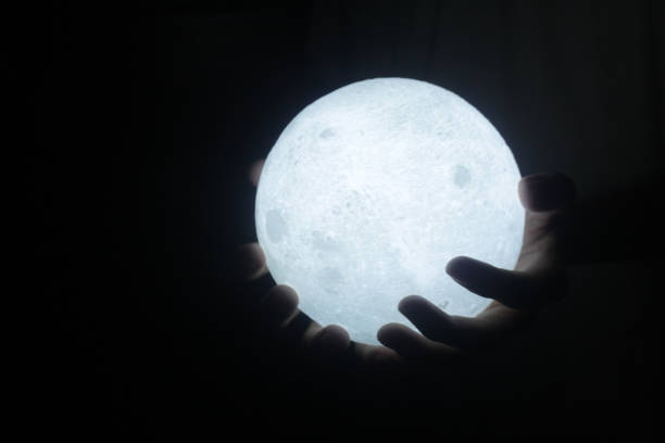 istock Warm white light of ball lamp in hand on dark background. 1362471445