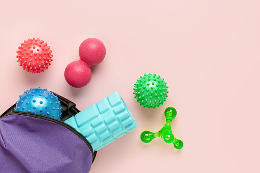 Balls,  hand massager and foam roller for myofascial release. Equipment for MFR. Tools for self-massage on pink background. Top view