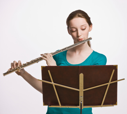 Teenage girl playing flute. Square shot.