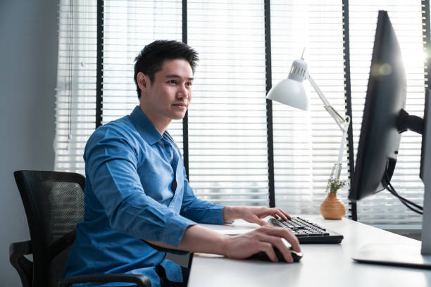 istock Asian handsome business man using laptop computer working in office. Attractive professional male employee worker sitting on table, feel happy and enjoy spending leisure time in corporate workplace. 1362484005