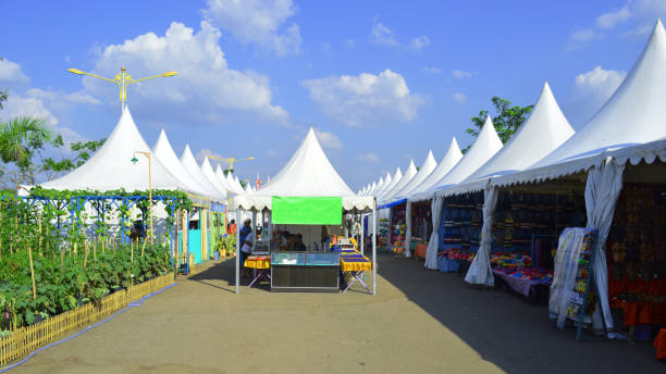white tents at the location of traditional handicrafts exhibitions and traditional market sellers by the roadside stock photo