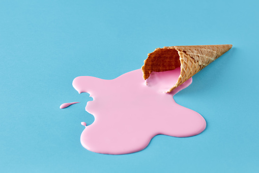 Helado rosa derritiéndose y derramándose del cono de gofre. Concepto minimalista de comida de verano. photo