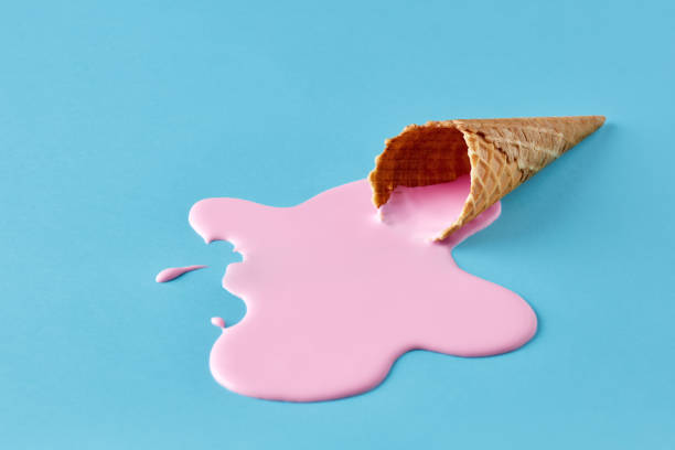 Pink ice cream melting and spilling from the waffle cone. Minimalistic summer food concept. Pink ice cream melting and spilling from the waffle cone on pastel blue background. Minimalistic summer food concept. spilling photos stock pictures, royalty-free photos & images