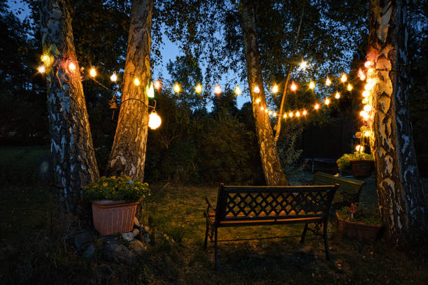 stringa di luci in giardino con panchina da giardino e angolo riparato nascosto da siepi la sera. - festa in giardino foto e immagini stock