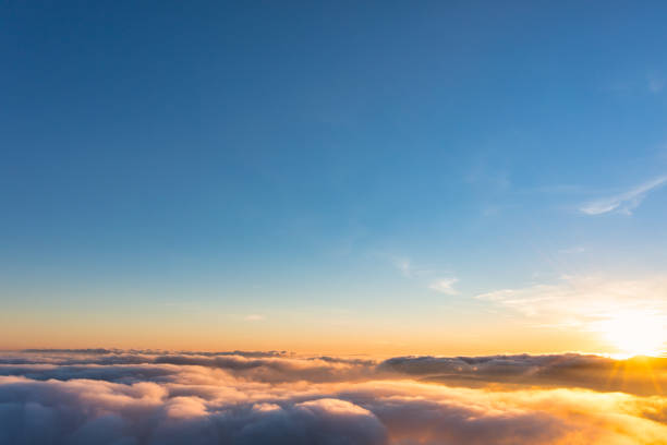 istock Sun shining above layer of white fluffy clouds at sunset 1362494638