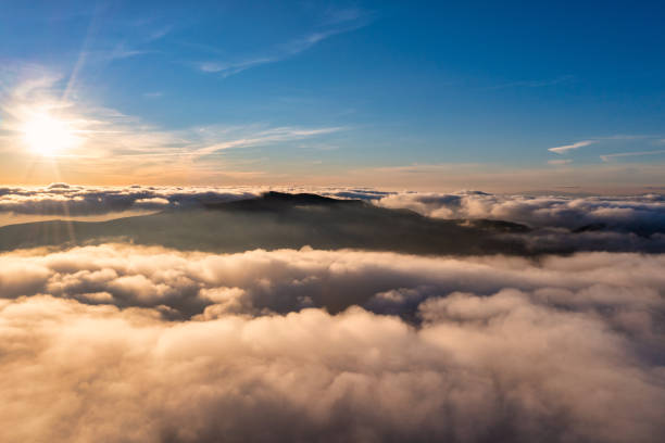 istock Sun shining above layer of white fluffy clouds at sunset 1362494663