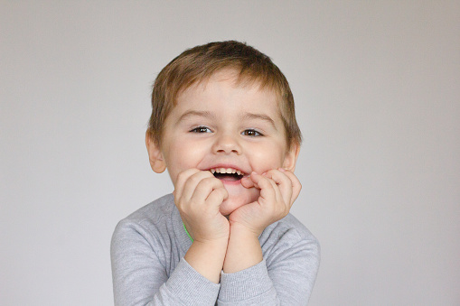 Handsome little boy in cardigan and shirt isolated on grey background