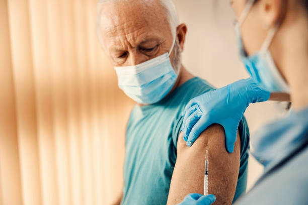 un homme âgé se faisant vacciner contre le covid 19 à l’hôpital. vaccination, inoculation et soins de santé. - injecting flu virus cold and flu doctors office photos et images de collection