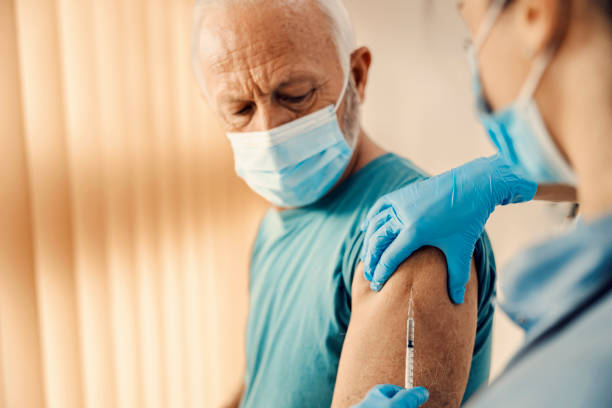 a senior man getting covid 19 vaccine in hospital. vaccination, inoculation and health care. - syringe injecting vaccination cold and flu imagens e fotografias de stock