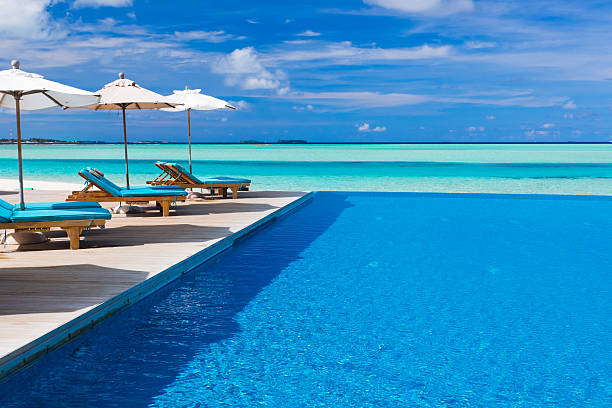 istock Deck chairs and a blue infinity pool over a tropical lagoon 136249763