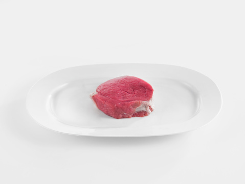 Raw steak in plate on white background