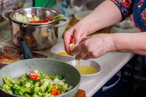 istock senior caucasian woman hands breaking white chicken egg above white bowl 1362499849