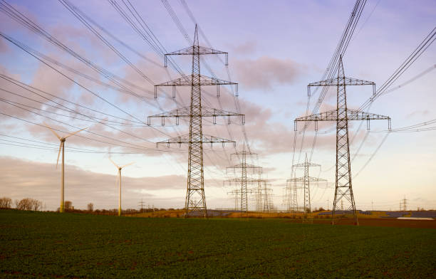 istock Electricity pylons and two wind turbines 1362501265