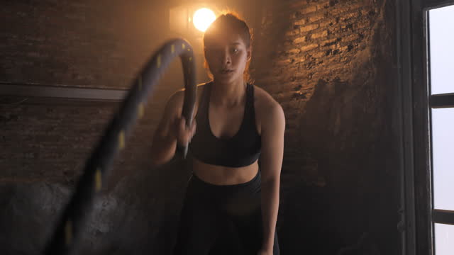 Fitness woman exercising with battle rope abandoned warehouse. Tough man working out in cross training gym made inside old factory. gym, workout, fitness, training, exercise, health, fit, sport, lifestyle, healthy club,