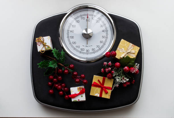 Analog scale surrounded by Christmas decorations and gifts. Overweight left after Christmas holidays. Start diet concept. stock photo