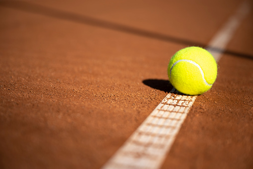 Close-up of tennis ball on the clay court.