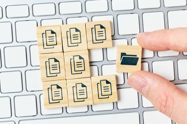istock Concept document management system or DMS. The person archives files in a folder. Hand and cubes on the keyboard. 1362513232