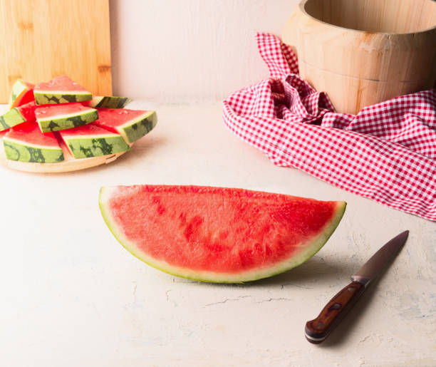 istock Piece of watermelon on white table at wall background with knife. 1362516593