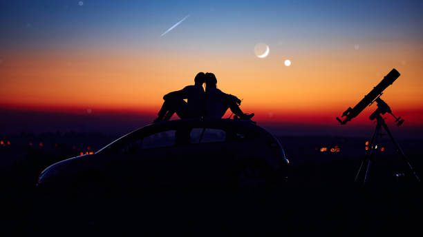 Couple stargazing together with a astronomical telescope.