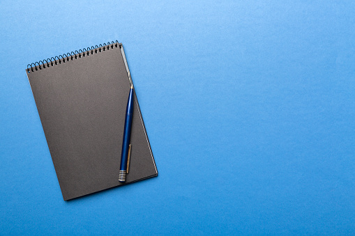 school notebook on a colored background, spiral black notepad on a table Top view.