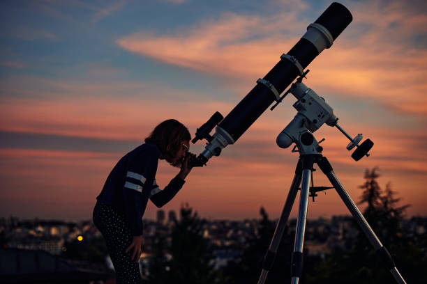 istock Girl with astronomical telescope stargazing under twilight sky. 1362517716