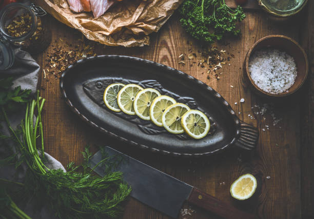 Fish cooking concept. Baking pan in fish shape with lemon slices on rustic background. Top view