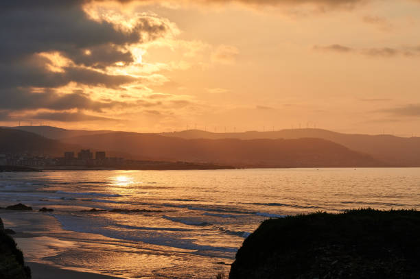 paysage à couper le souffle de mer calme et de plage sous un ciel ensoleillé orange vif avec des nuages le soir - dramatic sky dusk night sustainable resources photos et images de collection