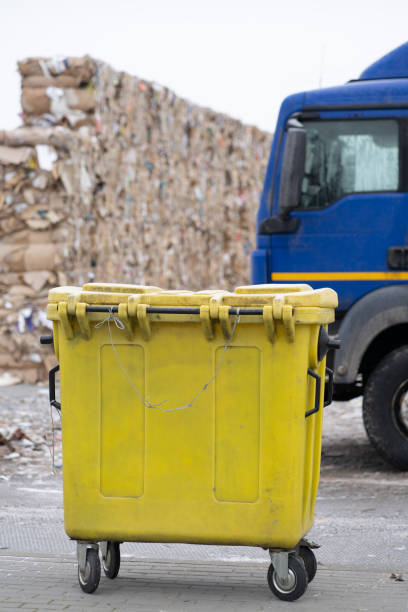 istock Yellow trash container on the background. Stack of paper waste beforeshreding at recycling plant. 1362527382