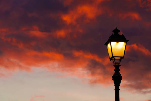 Old fashioned street lamp against beautiful sunset sky and colorful clouds