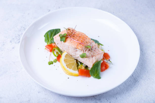 istock Trout (salmon) with vegetables, lemon and microgreens, cooked by the confit method. A traditional French dish. White background. Close-up. 1362527580