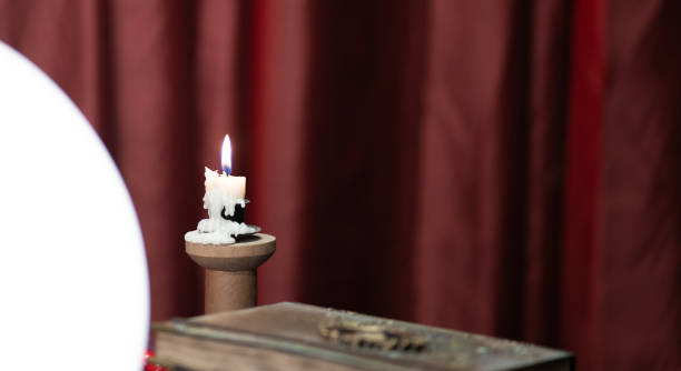 istock Crystal ball book and burning candle on the table 1362527695